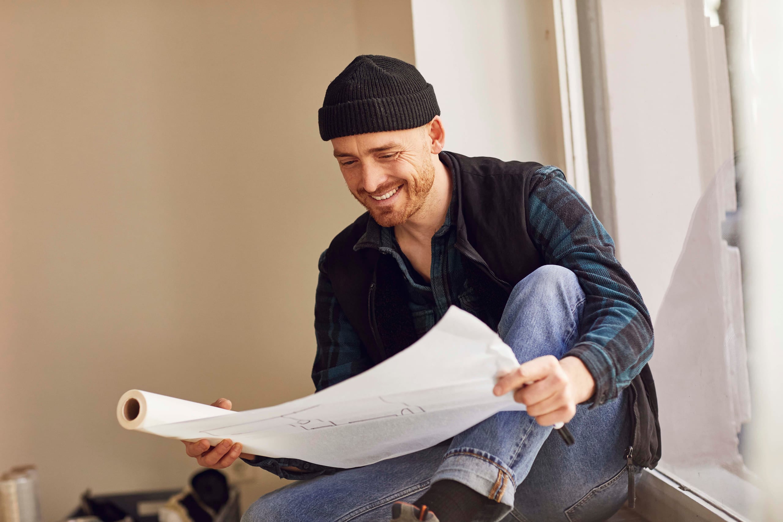 mann med lue leser en plan over arkitekturen