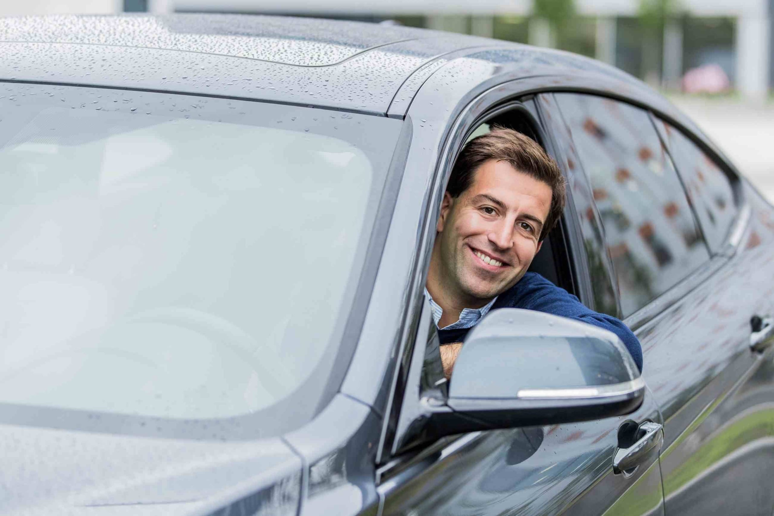 Ekspert på lån og renter, Henrik Eriksen, Santander Consumer Bank, sitter på førersiden i en bil, smiler og ser ut av vinduet