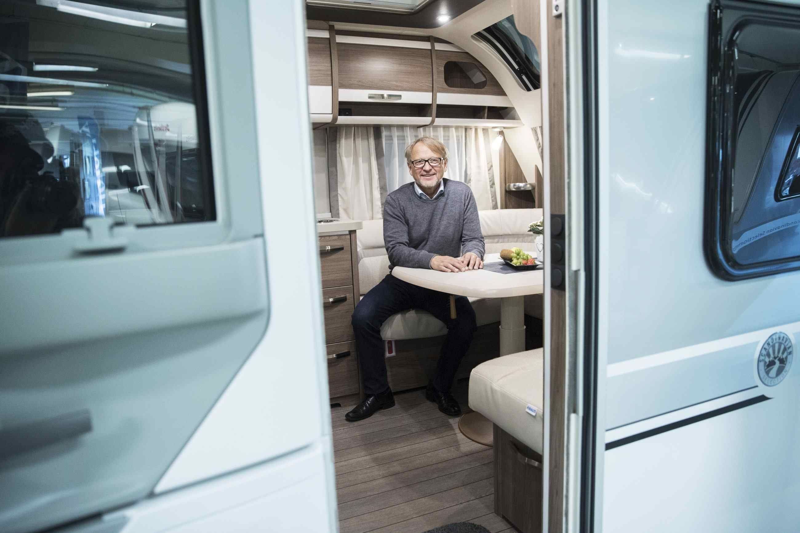 Geir Holm sitter ved spisebordet inne i en campingvogn