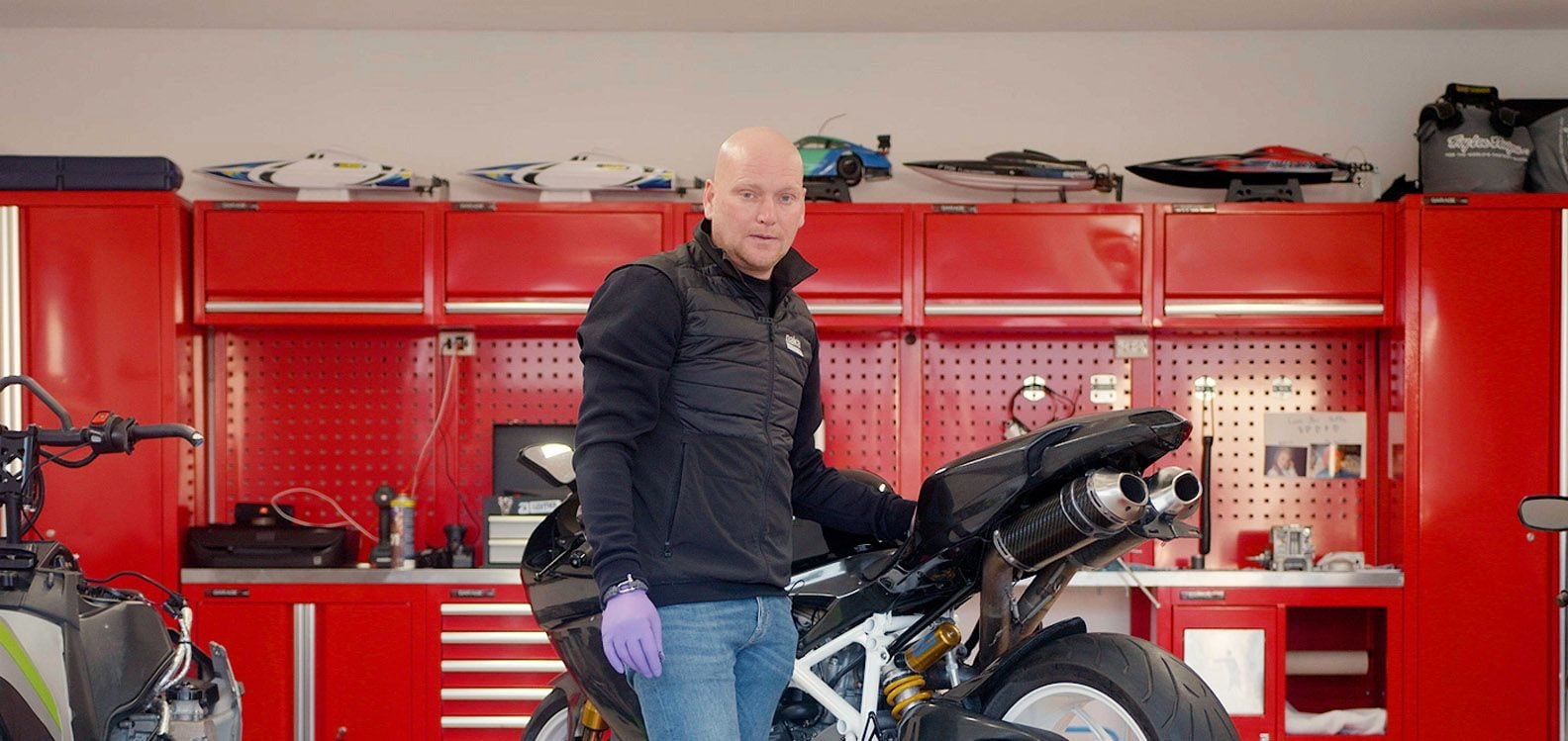 mann med en motorsykkel står inne i en garasje