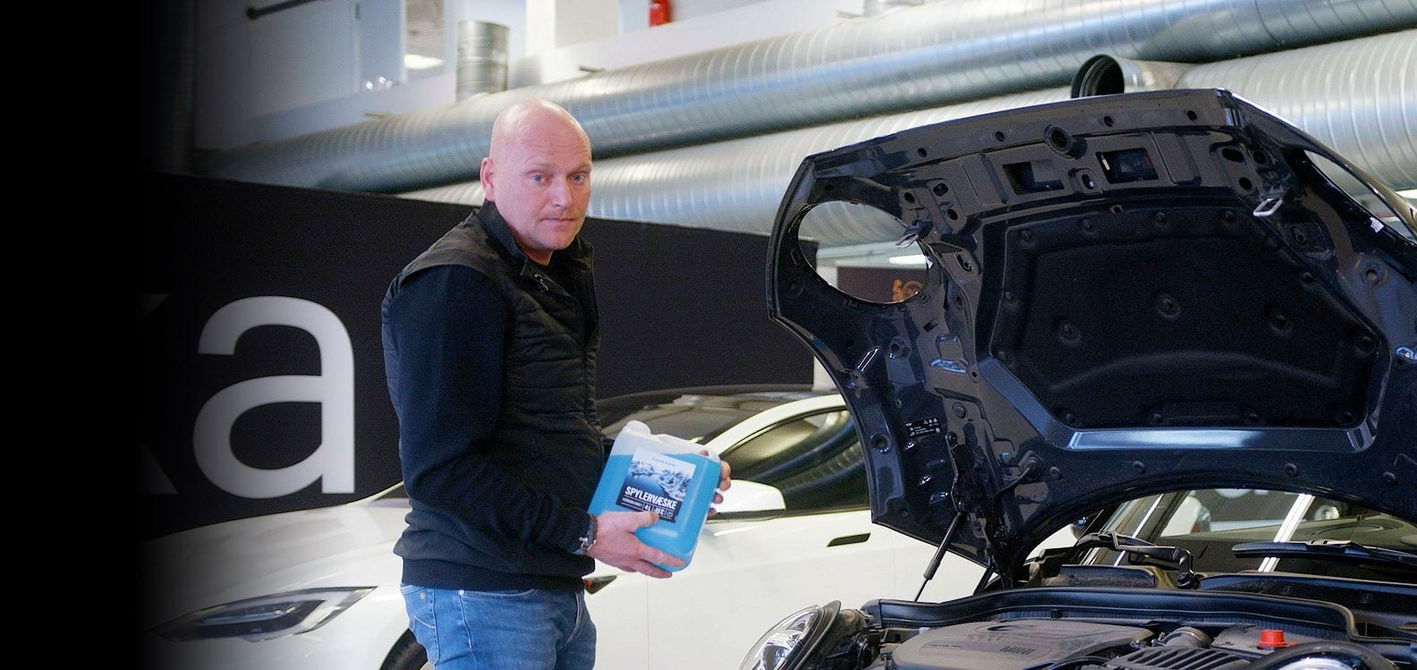 Mann fyller spylervæske på bilen sin